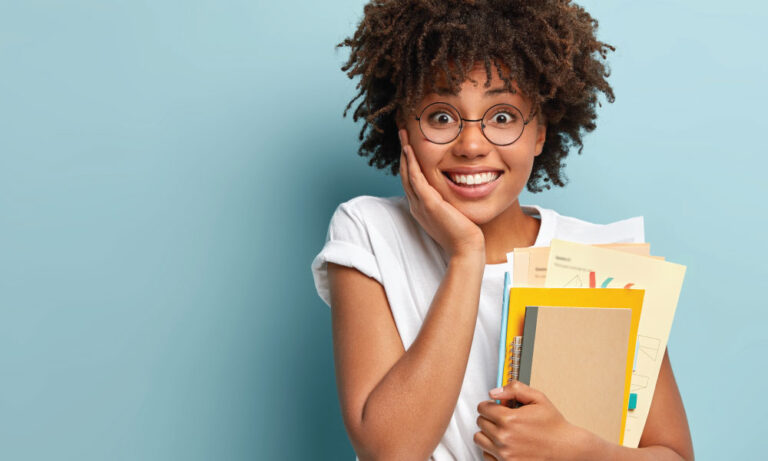 Estudante universitária sorrindo segurando livros e cadernos
