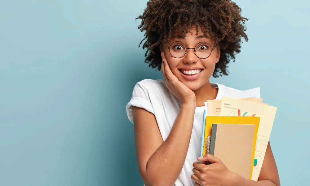 Estudante universitária sorrindo segurando livros e cadernos, simbolizando contribuição facultativa ao INSS desde os 16 anos